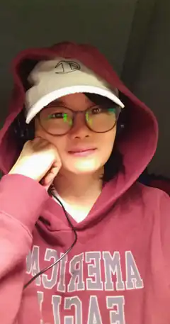 person in hoodie and cap resting chin on hand