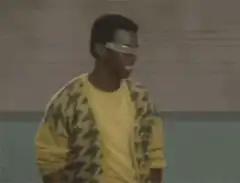 Man in yellow shirt and visor gives thumbs up