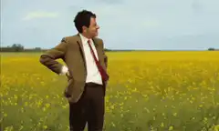 Man in field looks at watch and facepalms