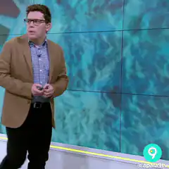 Man in glasses gestures and touches head