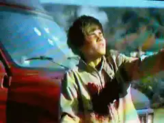 Boy shooting gun by red car