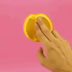 Hand squeezing orange slice