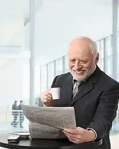 Old man laughing at newspaper with coffee