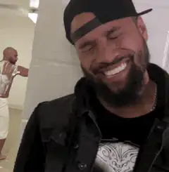 Man laughing while another man leans on wall