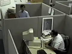 Man in cubicle hides from coworker