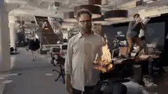 Oscar Isaac holding a flaming box in a chaotic office