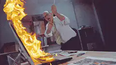 Man smashing burning laptop with hammer
