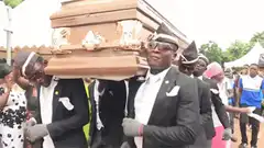 Men dancing while carrying a coffin