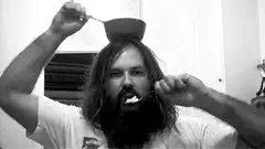 Bearded man eating cereal with bowl on head