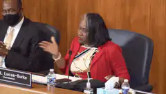 Woman in red jacket gesturing at hearing