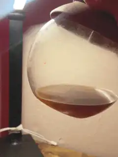 Hand holding a glass of amber liquid