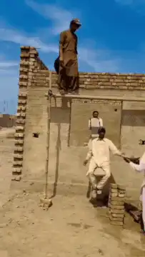 Man hanging from wall while another climbs down