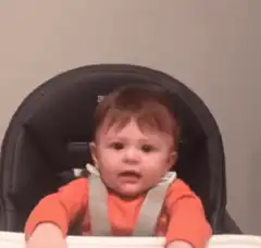 Baby raises arms in high chair