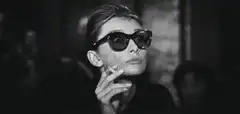 Audrey Hepburn smoking and taking off sunglasses