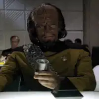Worf laughs while holding a cup