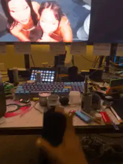 Two women on screen with hand holding phone