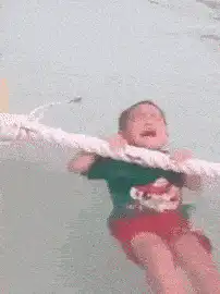 Crying baby held by rope in water