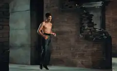 shirtless man dancing in brick room