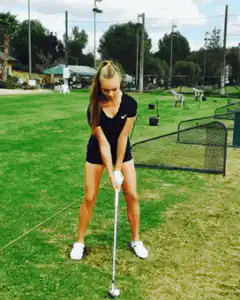 Woman swinging golf club at driving range