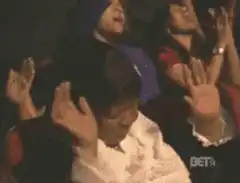 Woman in audience raises hands in praise
