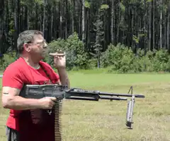 man smoking cigar with machine gun