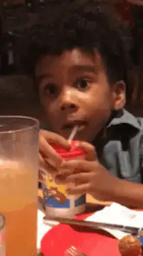 Wide-eyed boy drinking juice