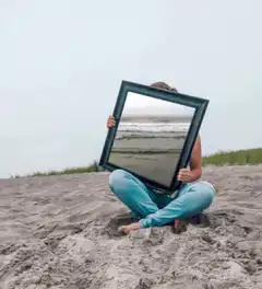 Person holding picture frame on beach
