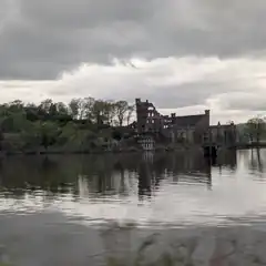 Old castle ruins by a lake under cloudy sky