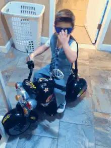 kid on toy motorcycle sunglasses