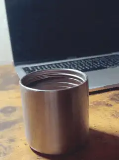 Empty metal cup on desk near laptop