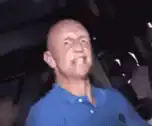 Bald man in blue shirt dancing excitedly
