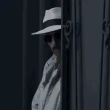 Man in fedora peeking through bars