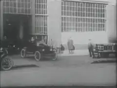 Vintage cars driving past factory