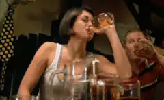 Woman chugs beer at a bar
