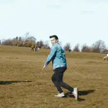 Man in blue jacket running across field