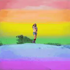 Man in rainbow outfit dancing on hill