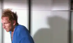 Man in blue robe drinks and looks out window