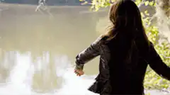 Woman throws rock into lake