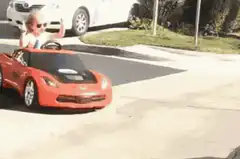 Toddler in toy car with middle fingers up