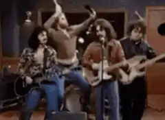 George Harrison playing guitar with drummer behind him