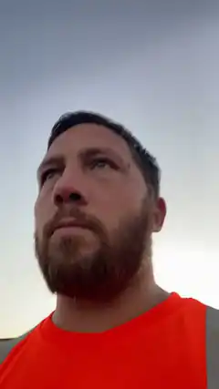 Man in orange shirt looking up at sky