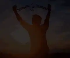 Man breaking chains at sunset