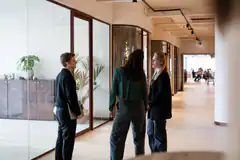 Three people talking in office hallway