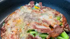 frying savory pancake with bacon and green vegetables