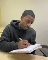 Man writing in notebook looks up confused