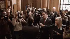 Man in suit surrounded by press