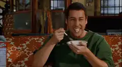Adam Sandler eating cereal with a smile