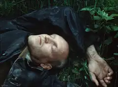 Man lying in grass with twitching mouth