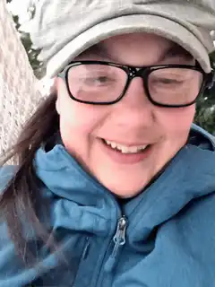 Woman in blue jacket and grey hat smiling