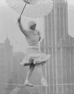 Woman tightrope walking with parasol